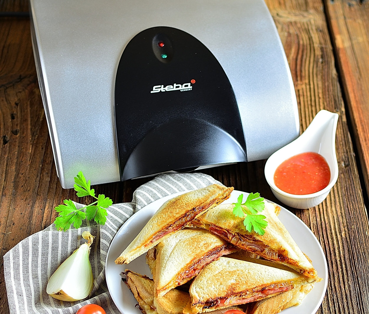 Sandwiches auf einem Teller neben einem Steba 4er-Sandwich-Maker »SG40«.