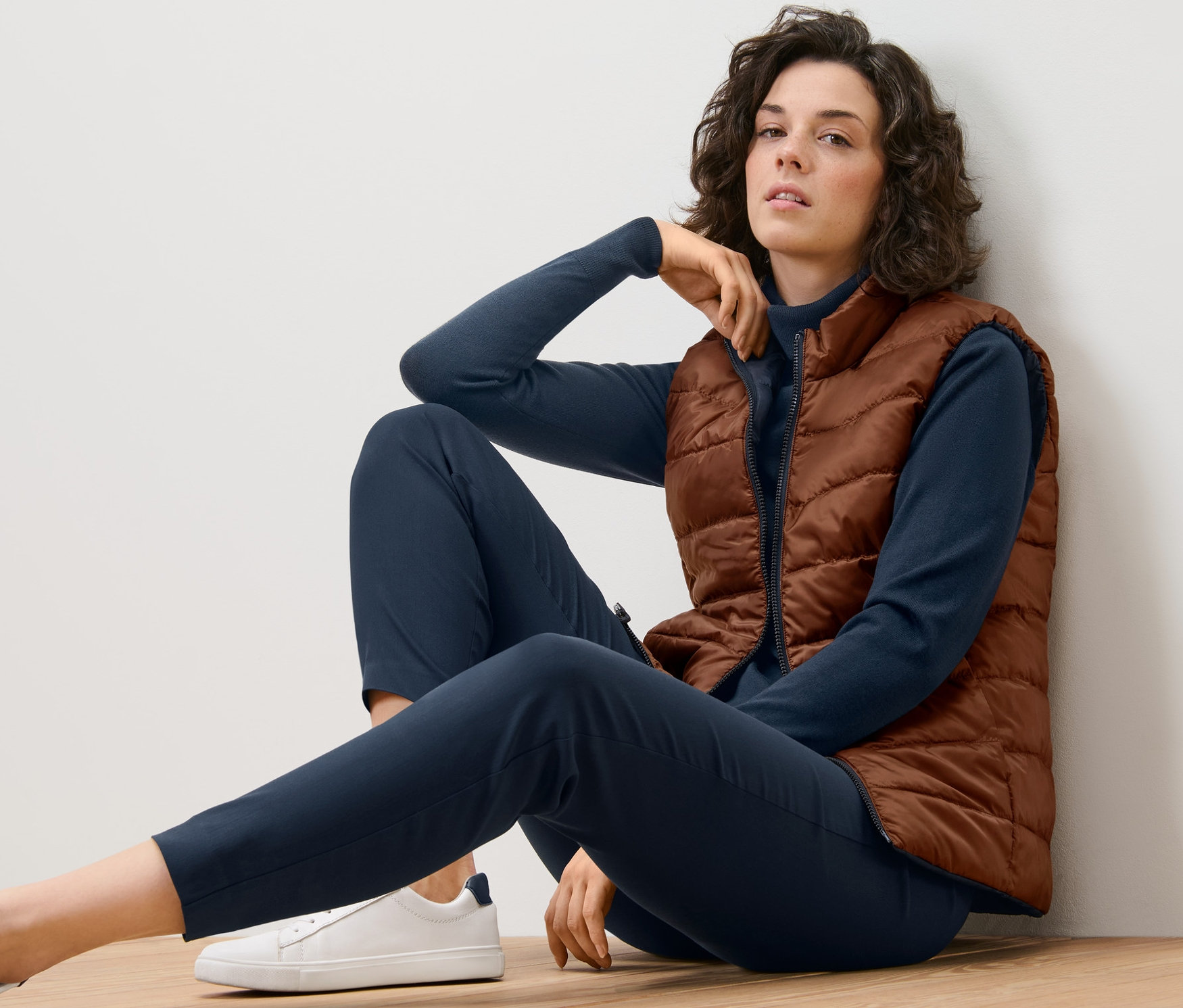 Frau sitzt auf dem Boden und trägt eine Wende-Steppweste.