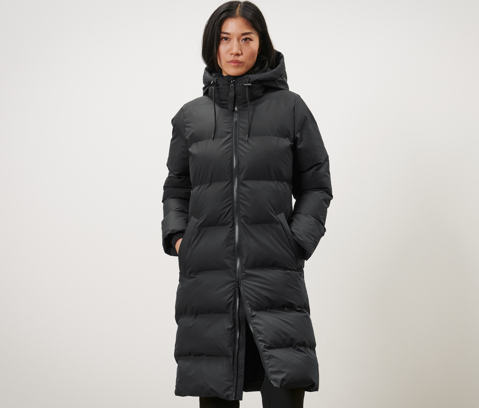 Frau trägt einen langen schwarzen Winter-Regenmantel.