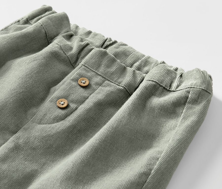 Detailaufnahme einer Kinder-Cord-Schlupfhose mit Gummibund und zwei Knöpfen.