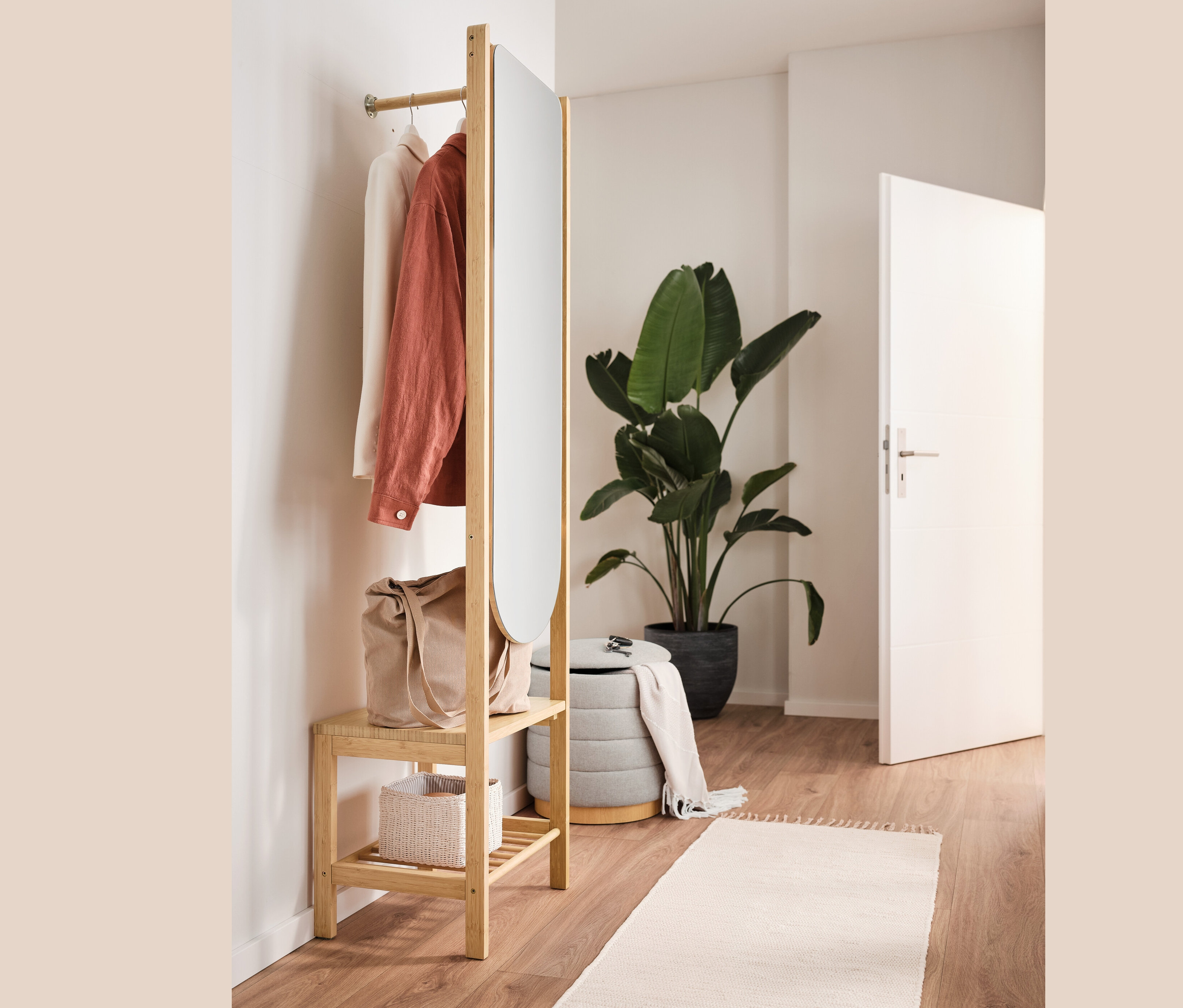 Garderobe mit Spiegel und Ablage, Pouf mit Stauraum, Tasche und Kleidung im Innenraum.