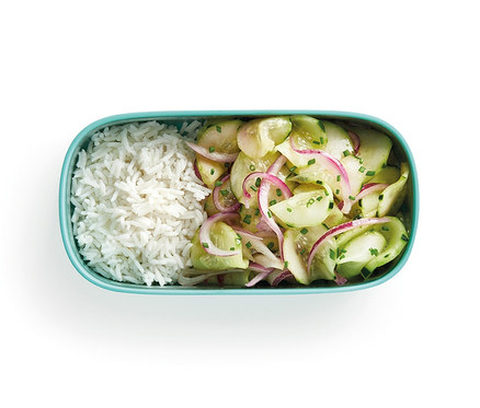 Draufsicht auf ein Lunch-Box-Set mit Besteck, das Reis und Gurkensalat enthält.