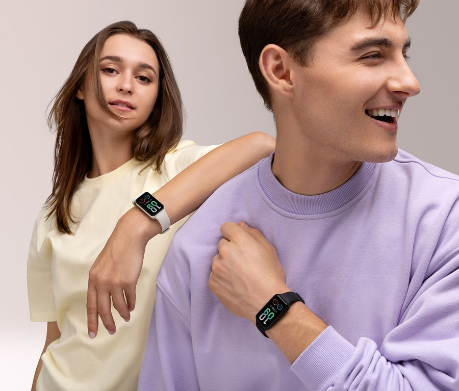 Ein junges Paar posiert. Die Frau trägt einen cremefarbenen Amazfit Band 7 Aktivitätstracker, während der Mann einen schwarzen Amazfit Band 7 Aktivitätstracker trägt.