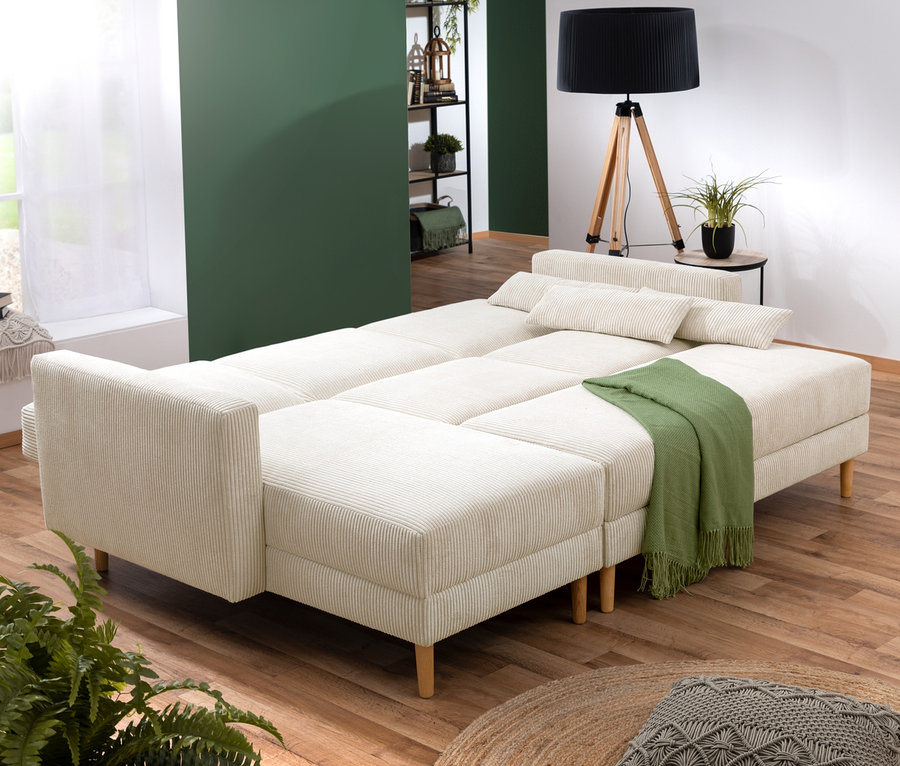 Ein cremefarbenes Federkern Eck-Schlafsofa "Jenna" steht im Wohnzimmer.