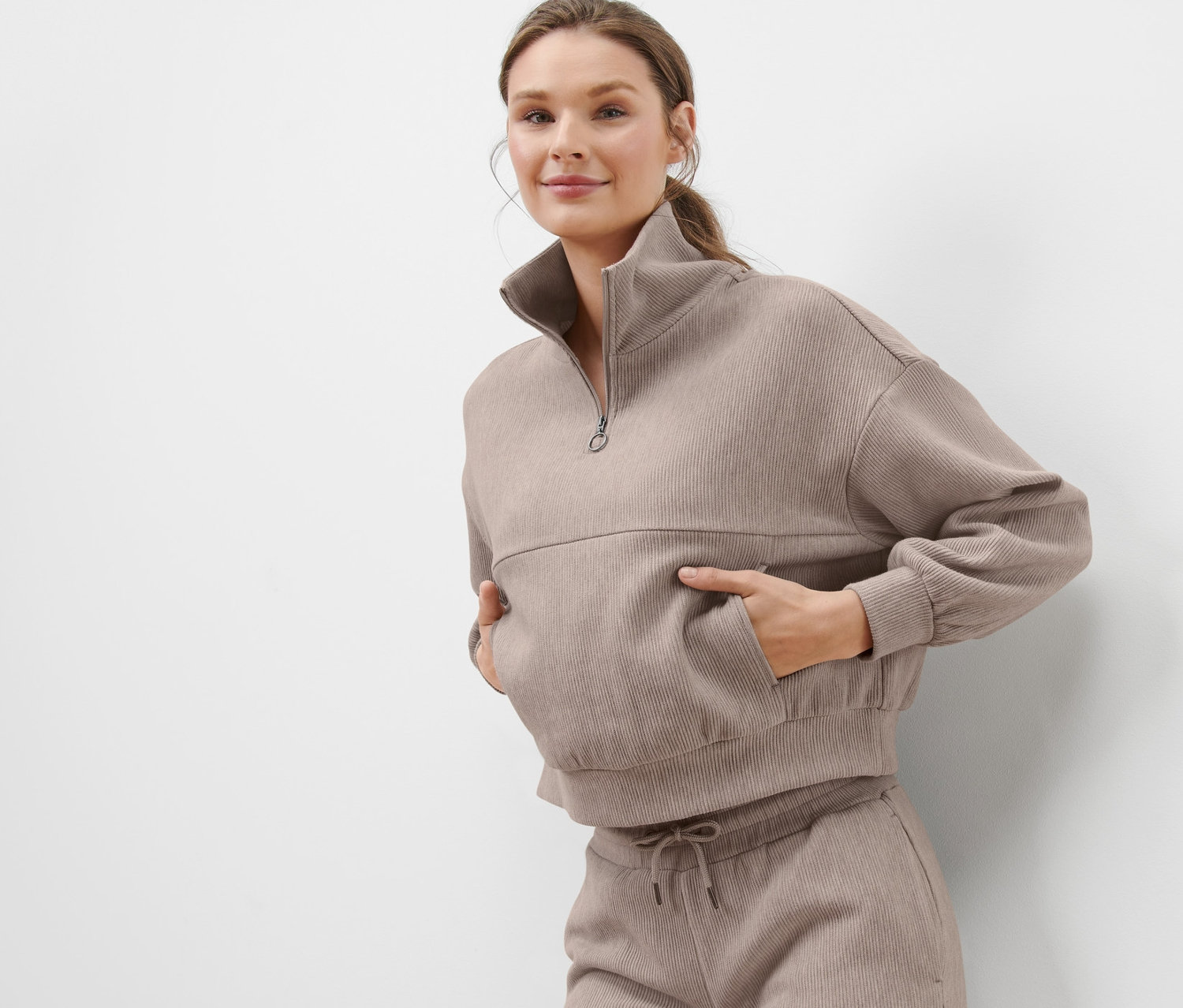 Frau posiert in beigem Sweatpullover.