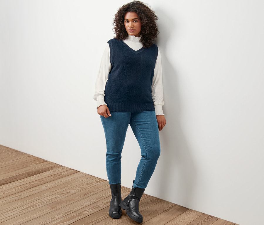 Frau posiert in Strick-Pullunder in Boucléoptik, Blusenshirt mit Stehkragen, creme und Treggings »Fit Nelly«.