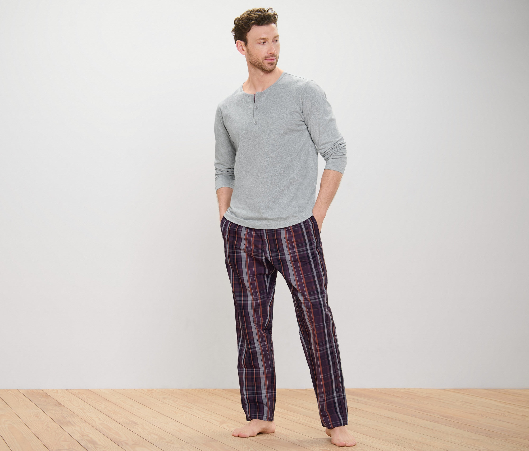 Mann trägt graues Pyjamaoberteil und gewebte Hose.
