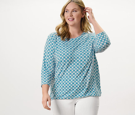 Frau posiert in Blusenshirt mit Alloverprint und 7/8-Stretchhose, weiß.