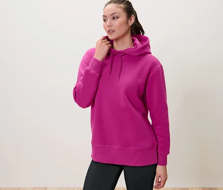 Frau berührt die Kapuze ihres Sweatpullovers mit Kapuze.