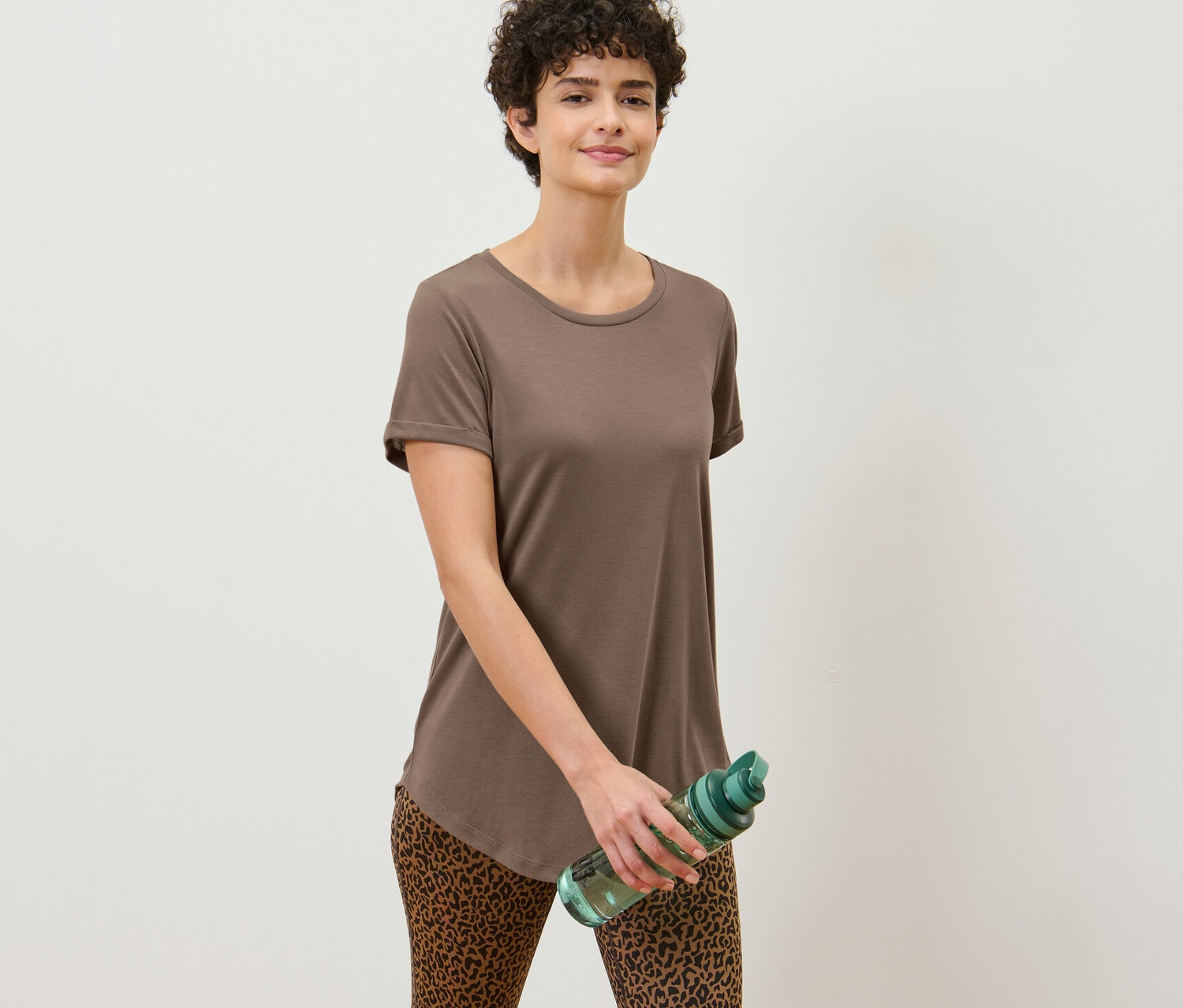 Frau hält eine Wasserflasche und trägt ein taupefarbenes Longshirt.