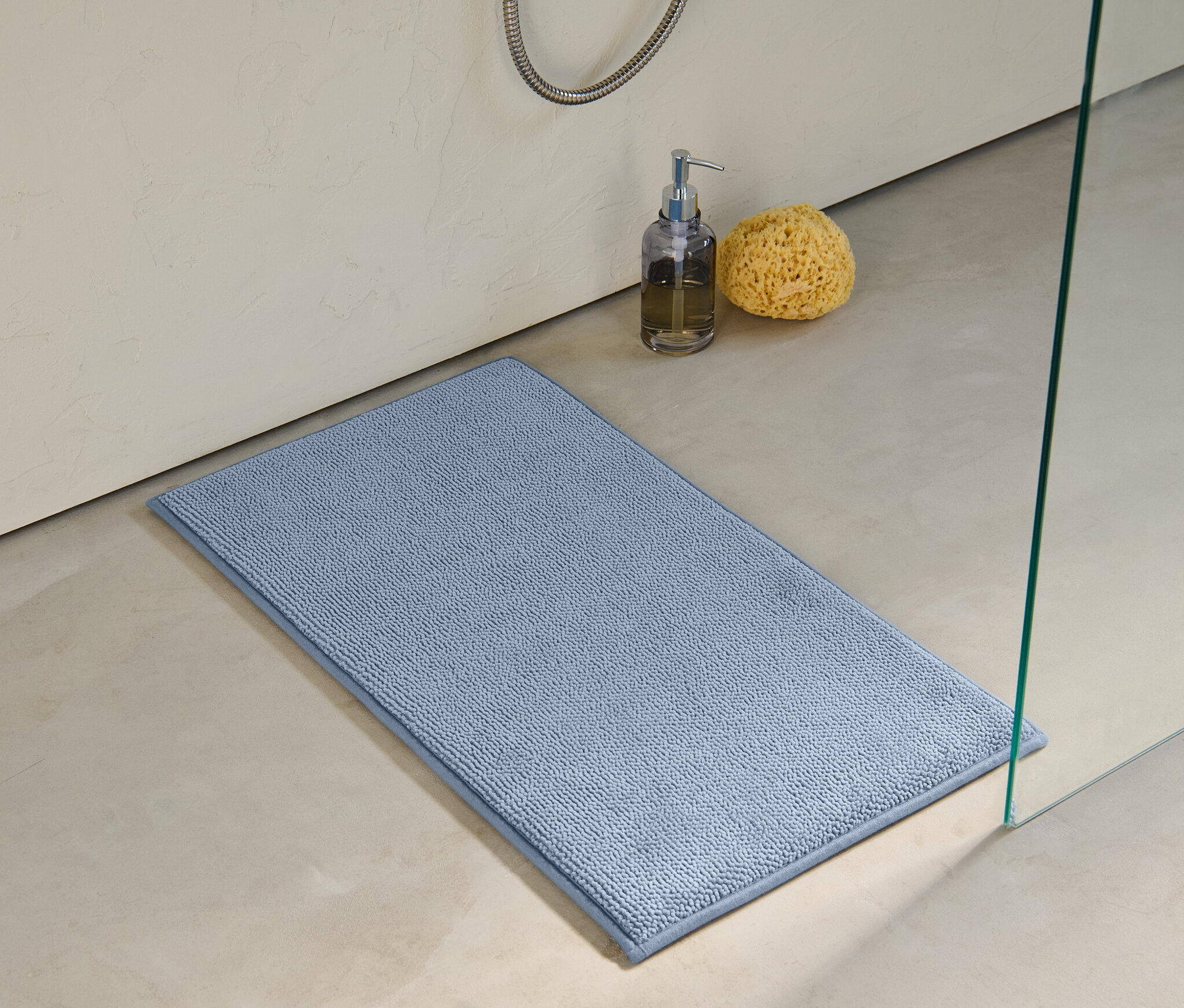 Eine blaue Komfort-Badematte, 40 x 70 cm, liegt auf dem Boden neben einer Dusche.