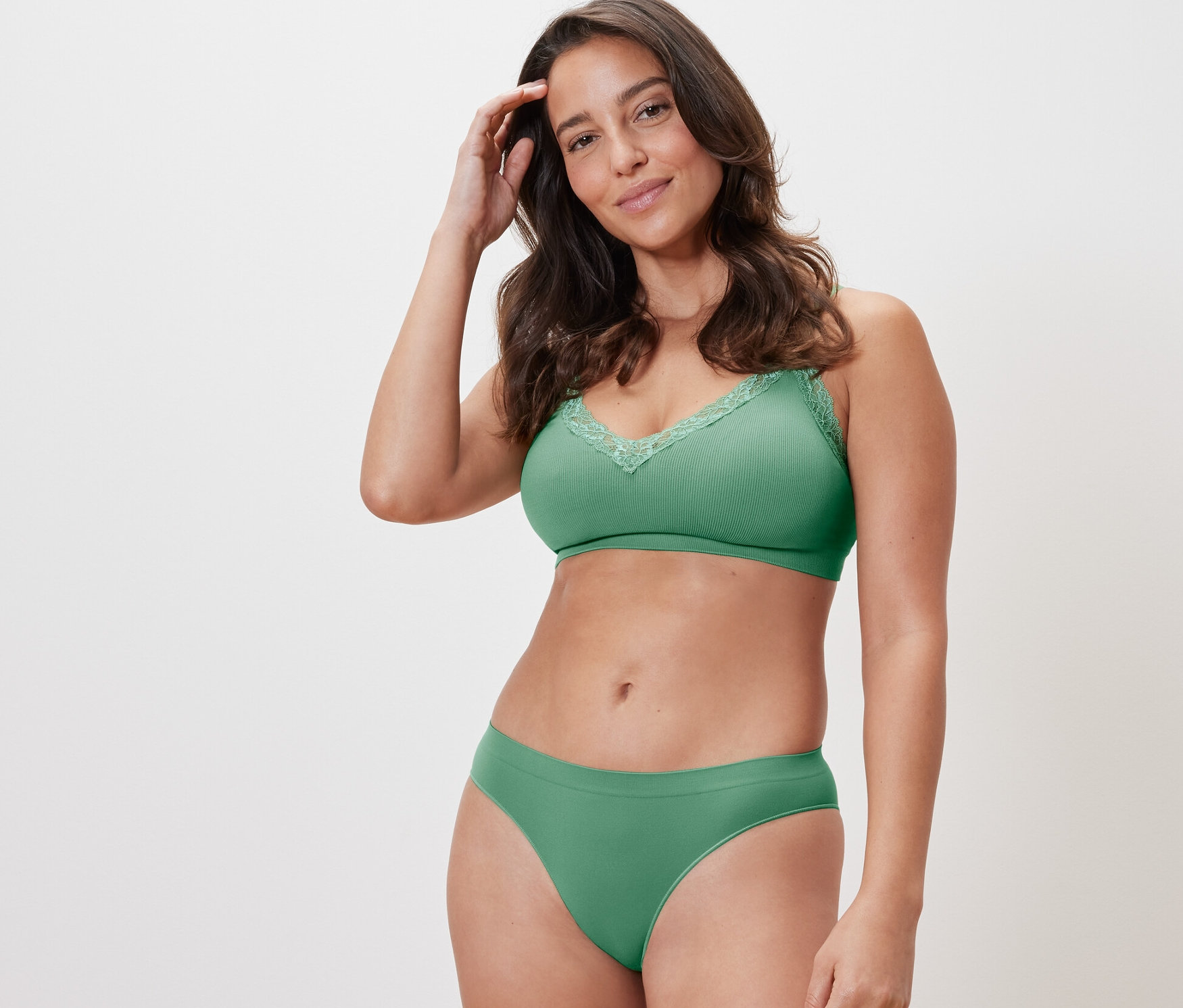 Frau posiert in grüner Unterwäsche. Sie trägt einen grünen BH und einen von zwei grünen Seamless-Slips.