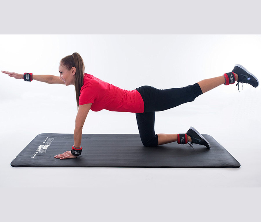 Frau macht Übungen auf der Christopeit Fitnessmatte »NBR« mit roten Gewichten an Handgelenken und Knöcheln.