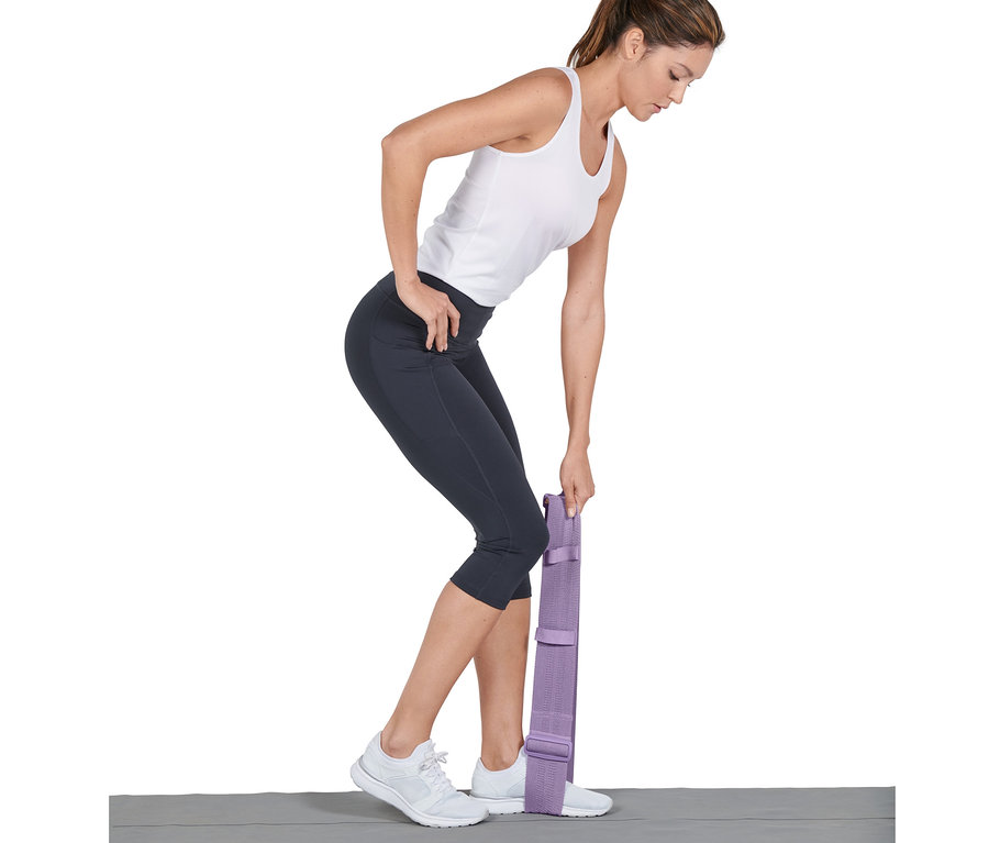 Frau trainiert mit verstellbarem Fitnessband, ein Fuß steht darauf.