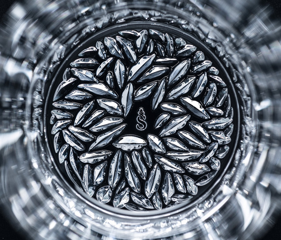 Detailansicht in ein Glas, in dem sich kleine silberne Blätter am Boden befinden.