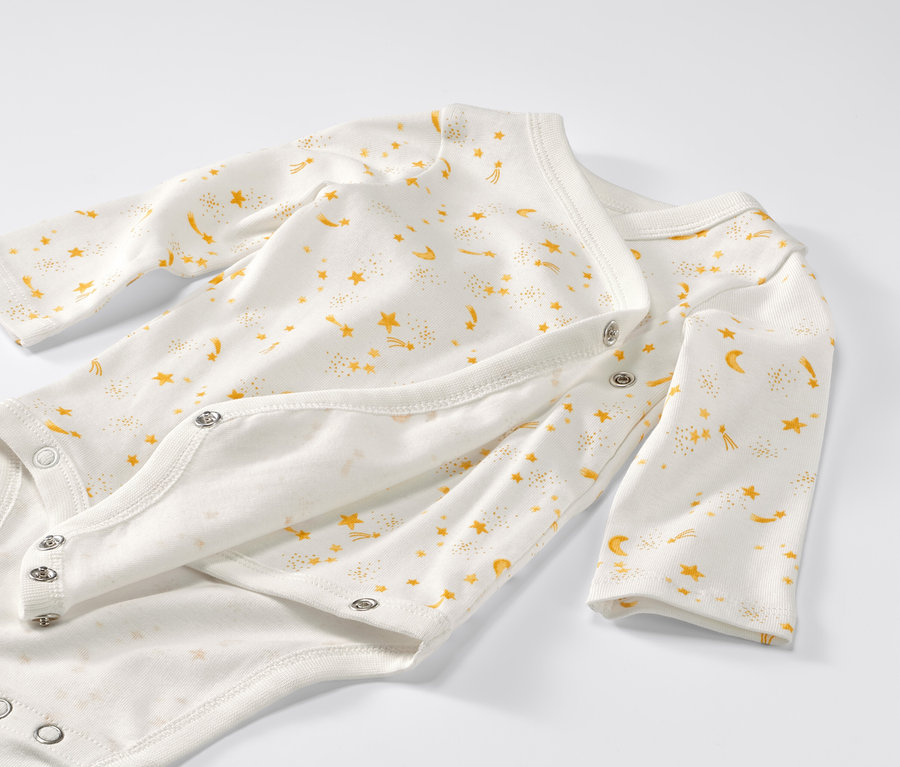 Detailansicht von 5 Baby-Bodys mit Mitwachsfunktion und Sternenmuster.