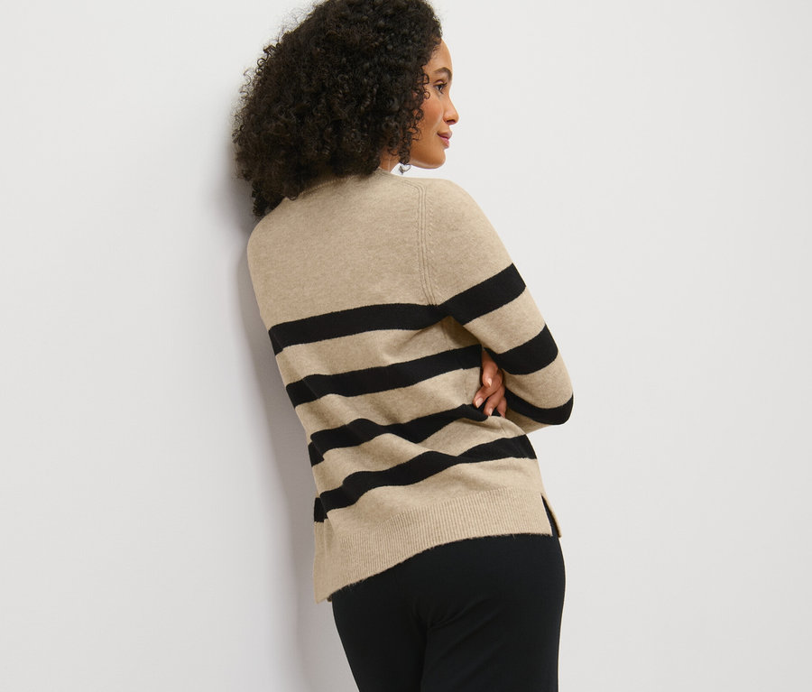 Frau posiert in gestreiftem Strickpullover.