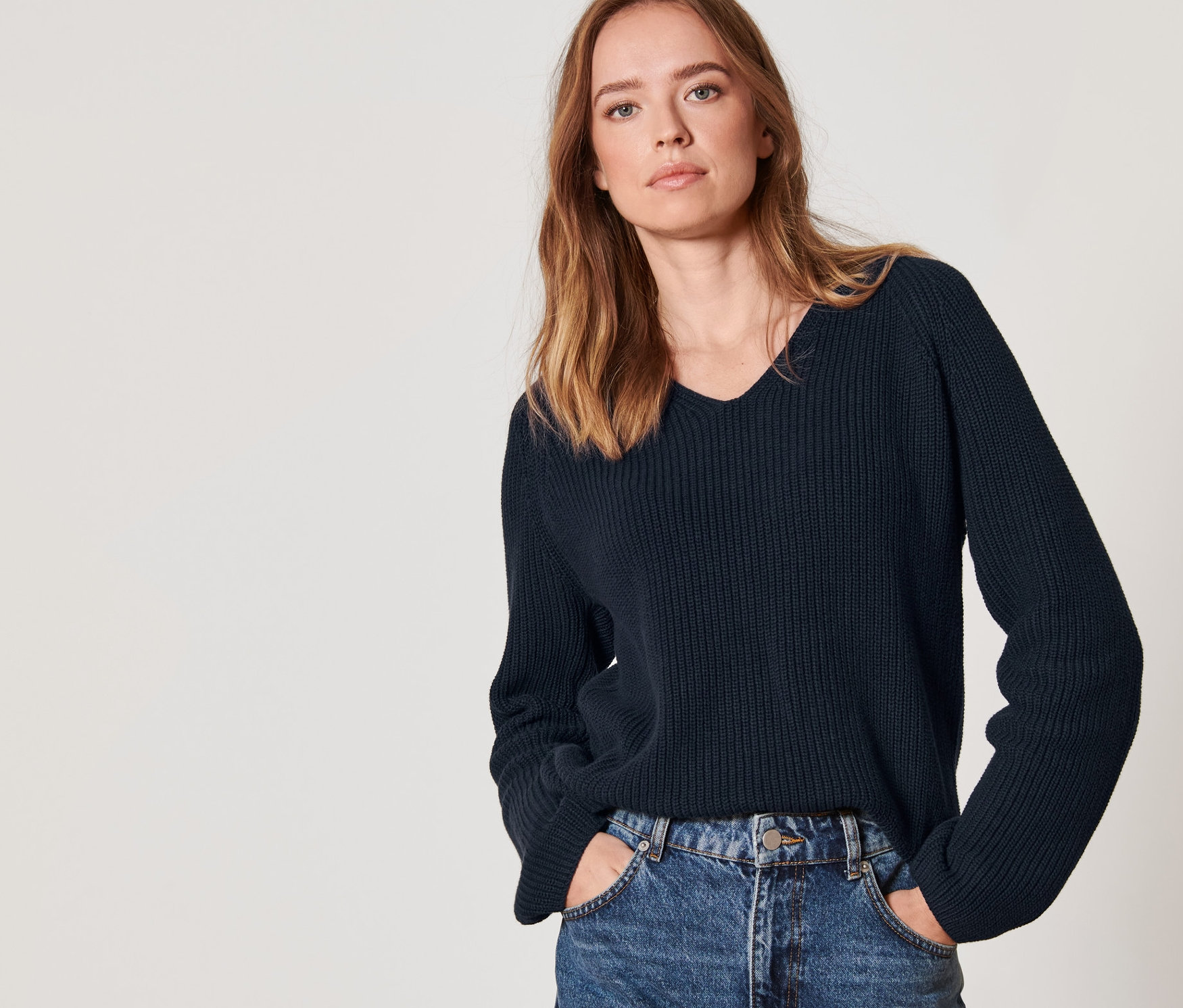 Frau posiert in marineblauem Strickpullover.