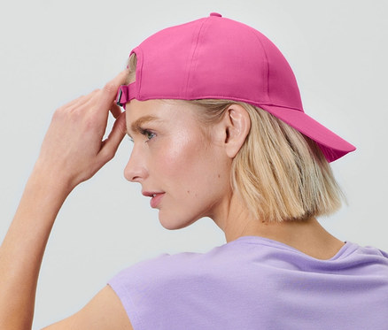 Blonde Frau sitzt und trägt eine Sportkappe.