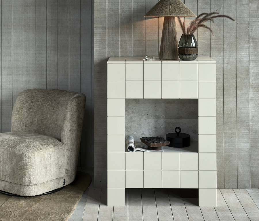 Sandfarbener Woood Drehsessel Atty neben weißem Schrank mit Lampe und Vase.