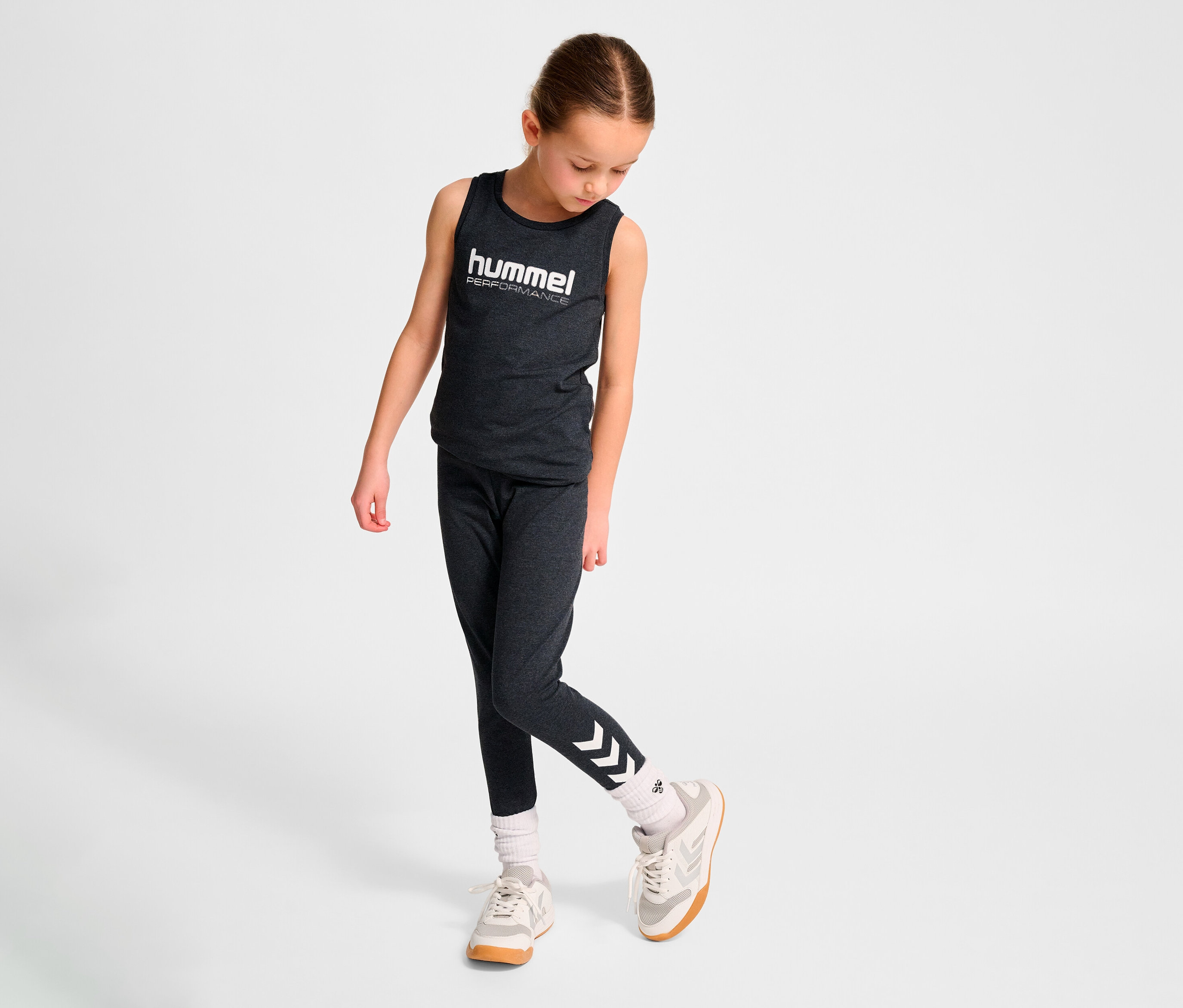 Junges Mädchen trägt ein Tanktop und die HUMMEL HMLJR Logo Tight.