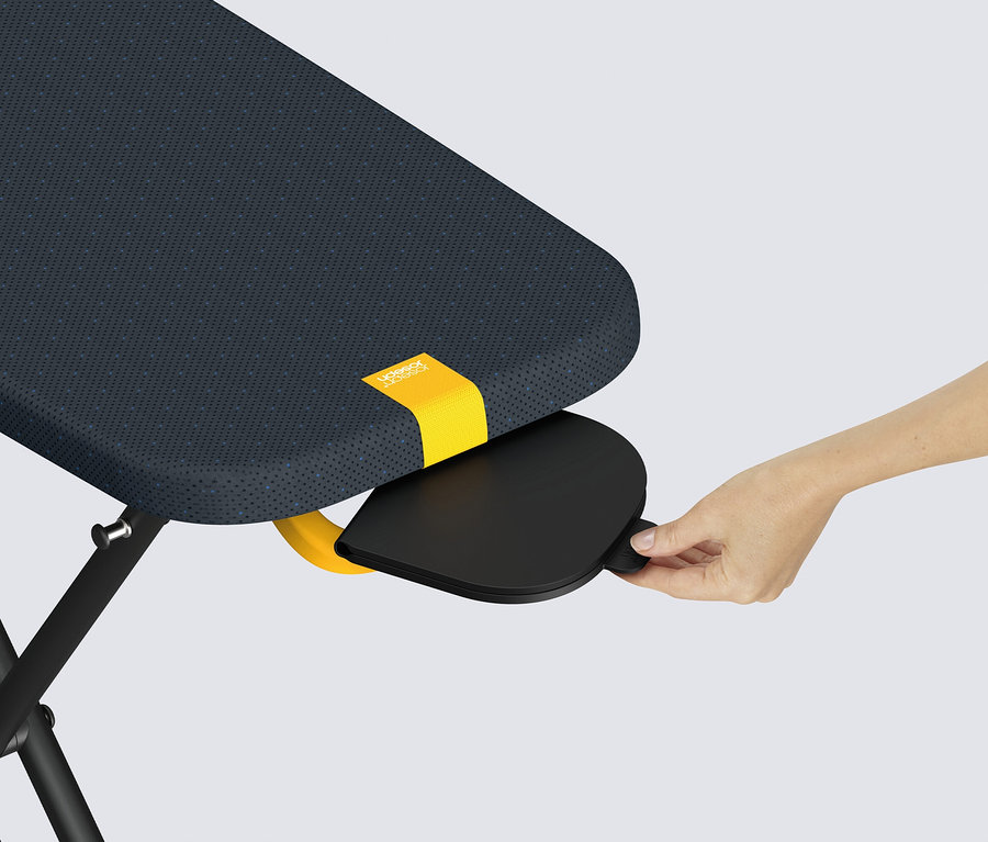 Eine Hand zieht eine schwarze Ablagefläche unter einem blauen Tisch mit gelbem Streifen hervor.