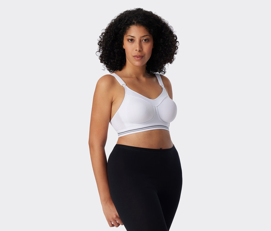 Frau mit lockigem Haar trägt einen weißen Sport-BH und schwarze Leggings.