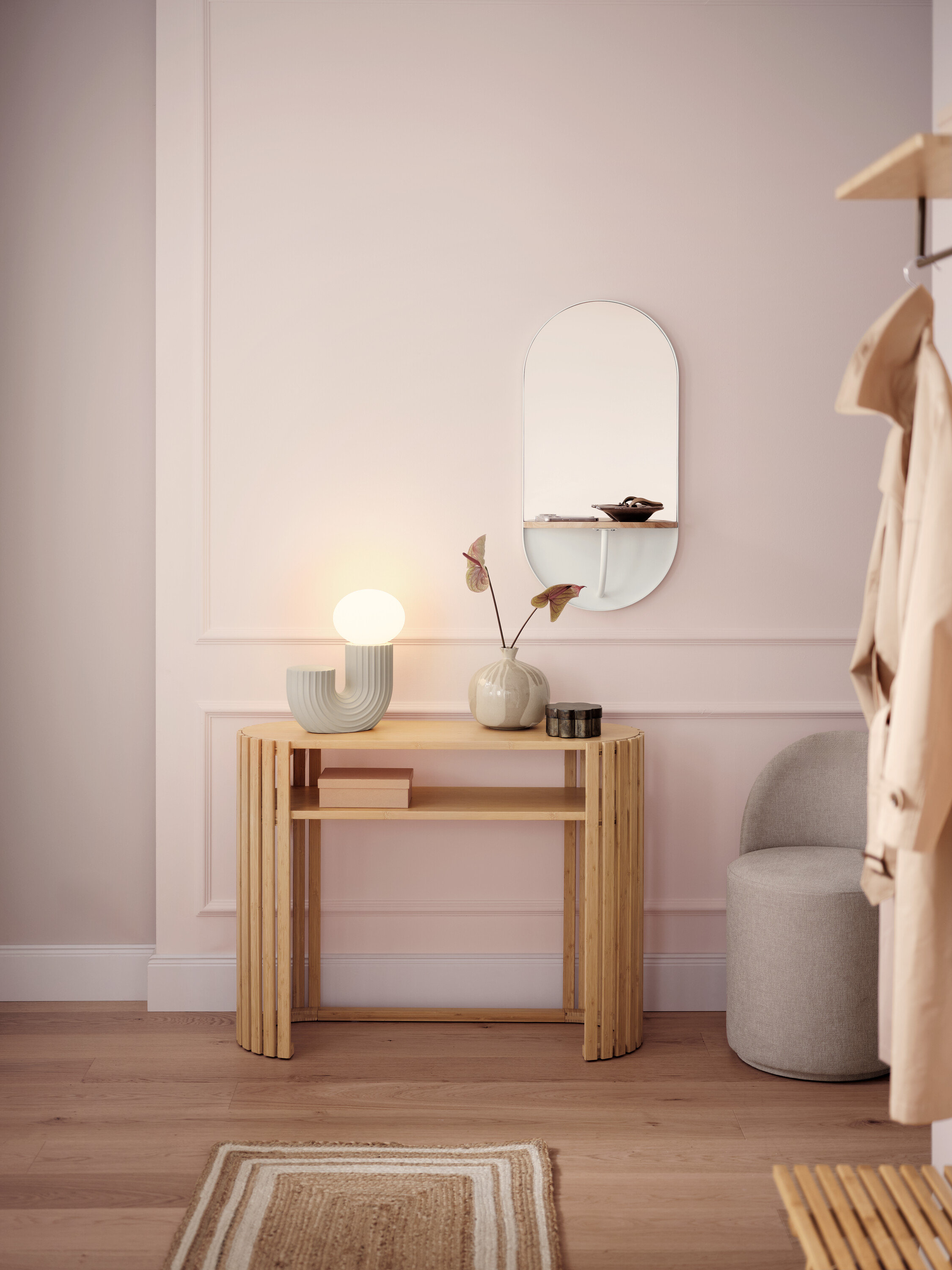 Heller Flur mit einem hölzernen Konsolentisch, einer Lampe, einem Spiegel und einem grauen Hocker.