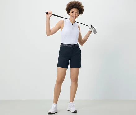 Frau hält Golfschläger über den Schultern und trägt dunkelblaue Softshell-Funktionsshorts.