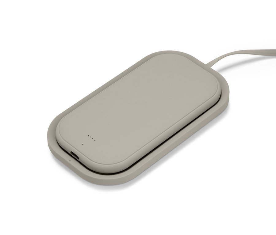 Eine graue, kabellose Powerbank mit Ladegerät liegt auf einer weißen Oberfläche.