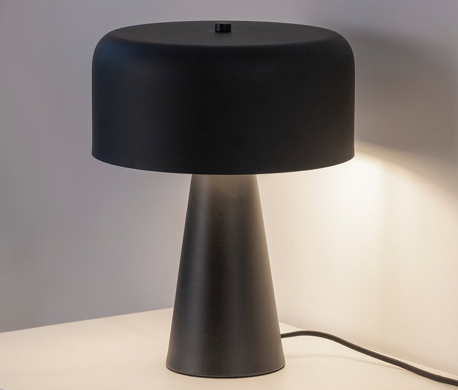 Eine schwarze Tischlampe auf einem weißen Tisch.