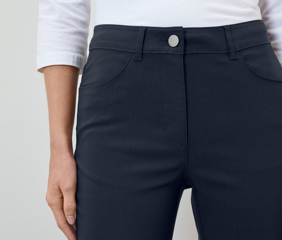 Frau trägt dunkelblaue Hosen und ein weißes Hemd.