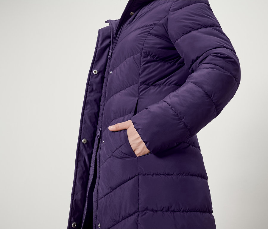 Detailaufnahme einer lila Steppjacke mit einer Hand in der Tasche.