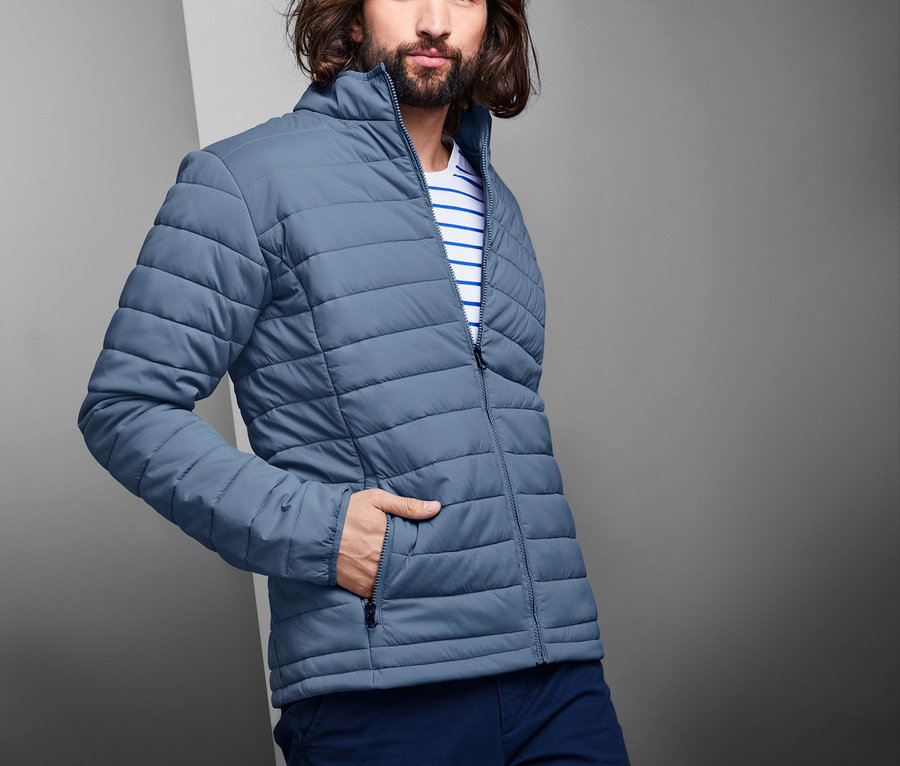 Mann posiert in blauer Steppjacke.