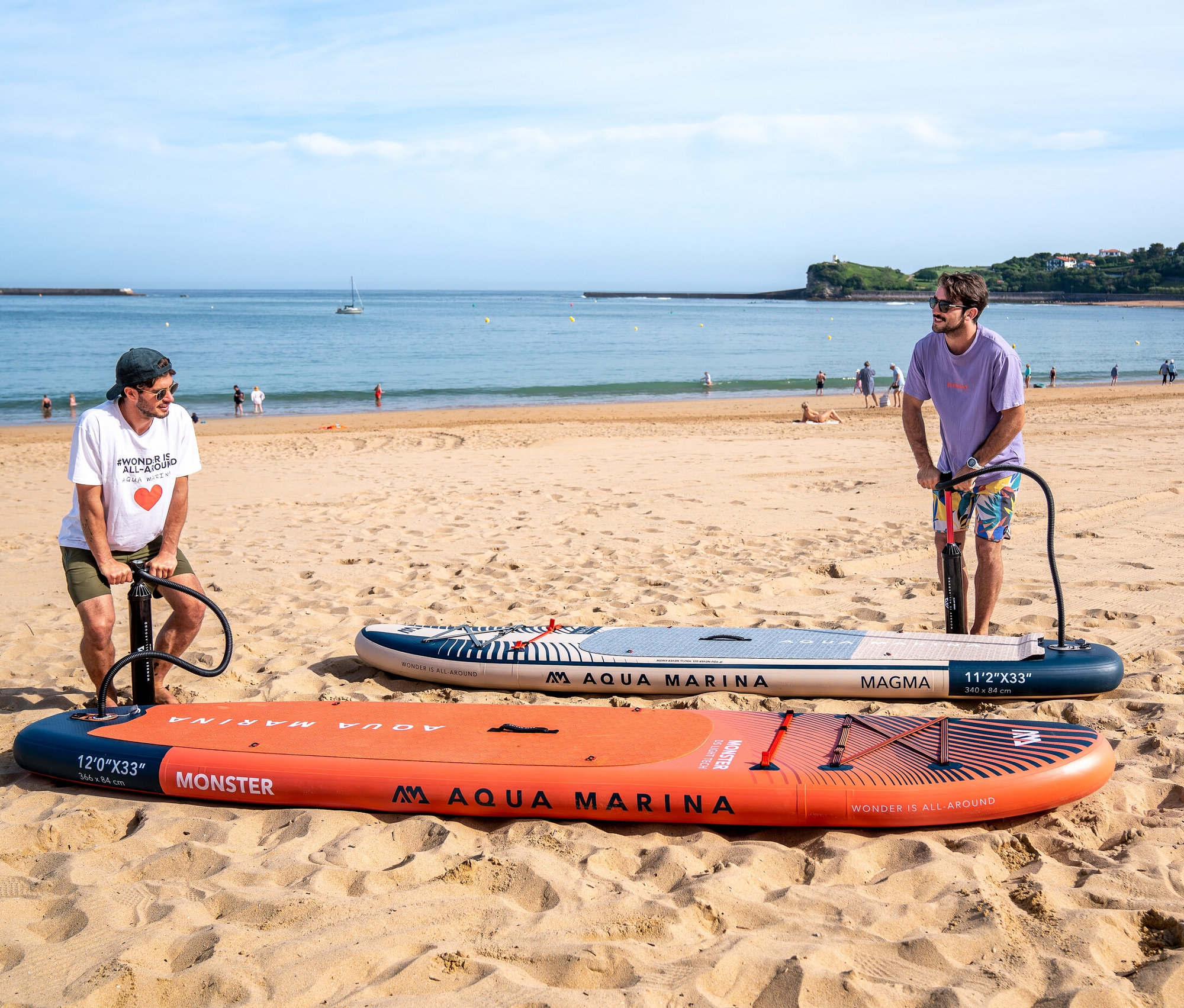 Zwei Männer pumpen Aqua Marina SUP Boards am Strand auf.
