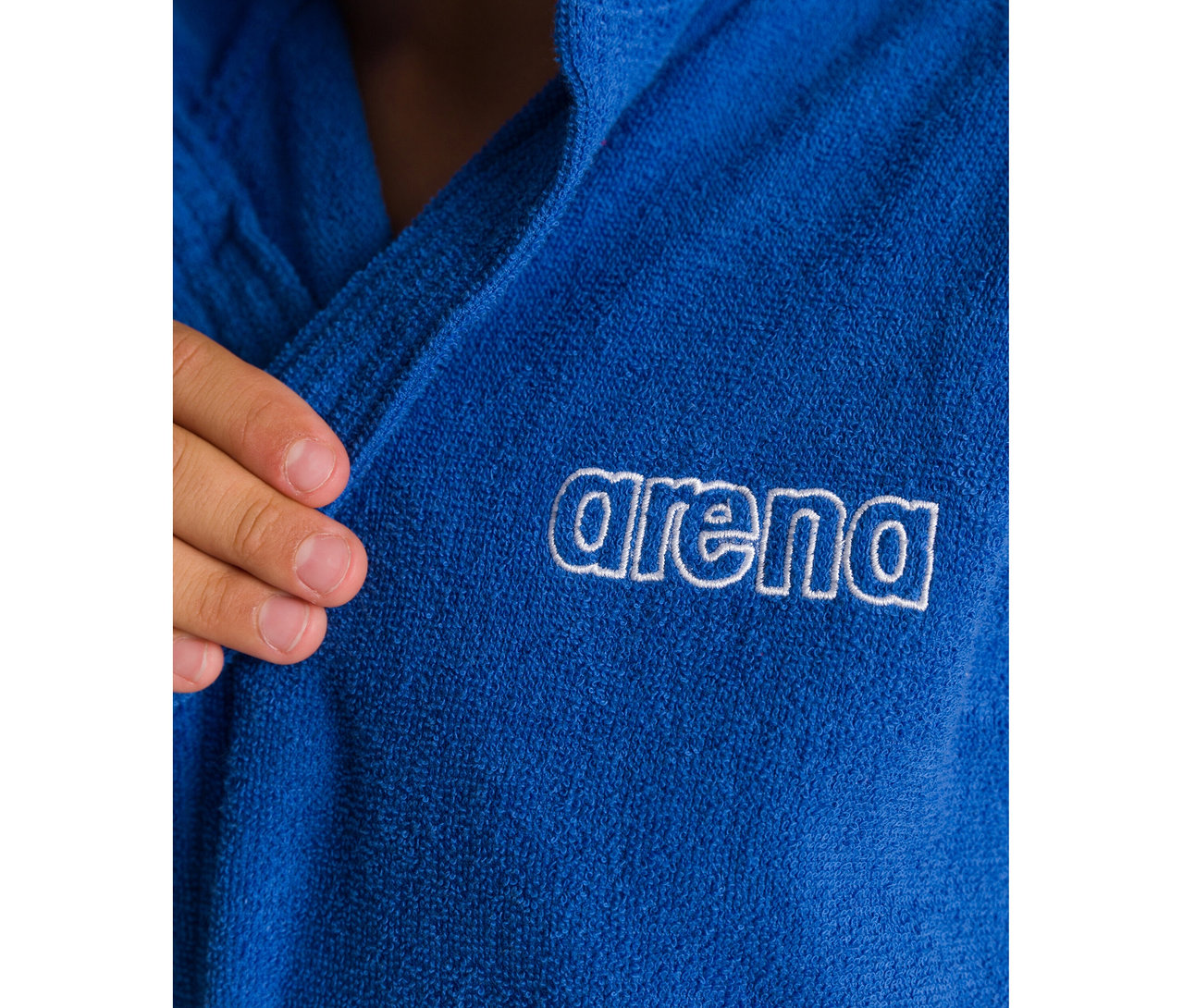 Nahaufnahme eines blauen arena Kinder-Bademantels Zeppelin Light JR mit weißem Logo, von einer Hand gehalten.