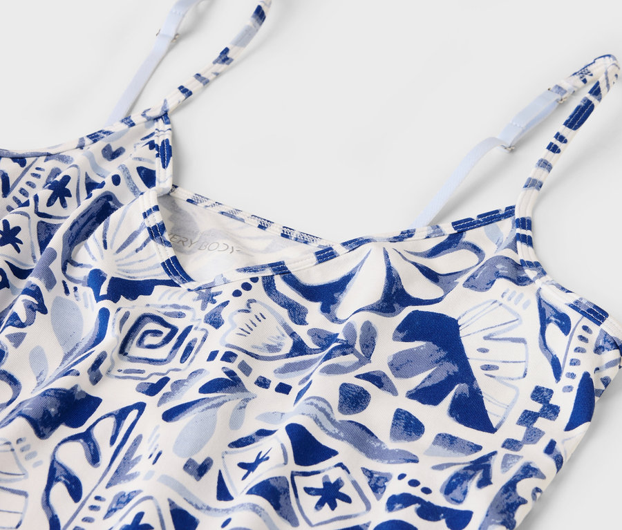 Nahaufnahme eines weißen Tanktops mit blauem Muster und dünnen, verstellbaren Trägern.