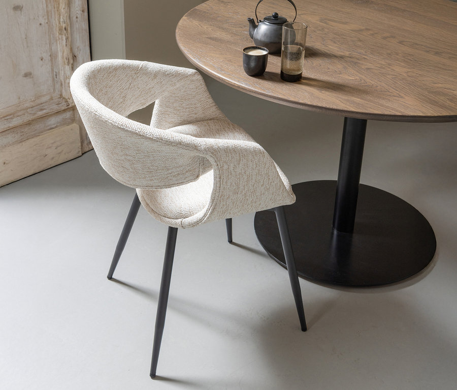 Ein einzelner WOOOD Esszimmerstuhl »Yossi« mit Metallfuß, schwarz-naturfarben, steht neben einem runden Tisch mit Teekanne und Gläsern.
