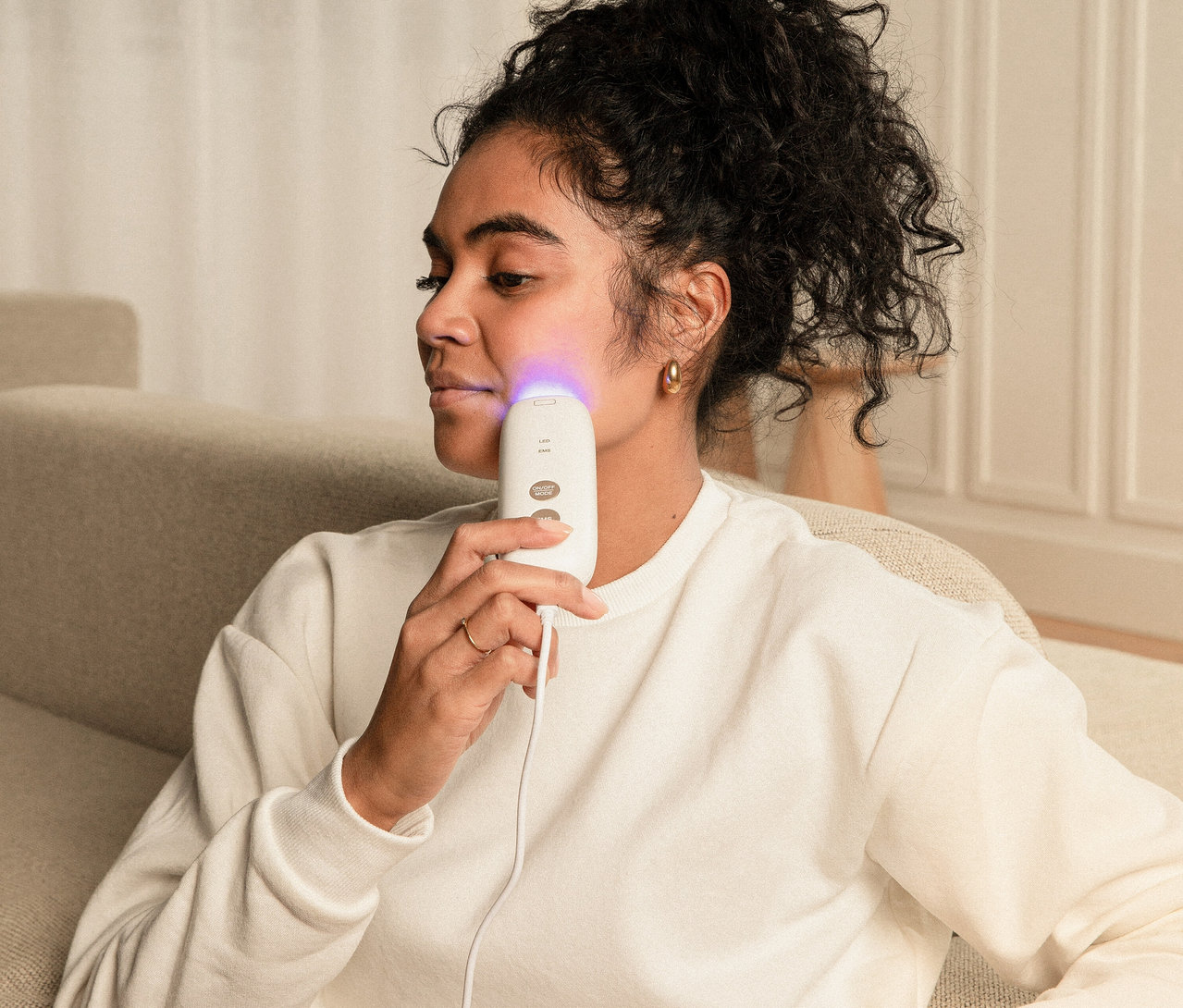 Frau hält Silk'n LED Face Mask mit EMS an ihr Gesicht.