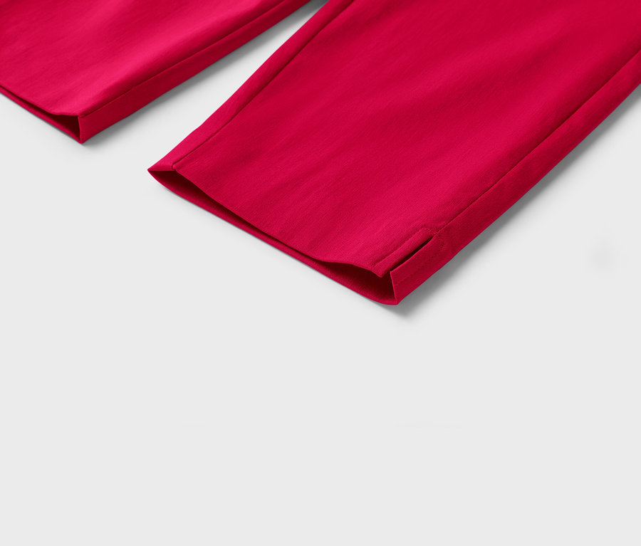 Detailaufnahme von roten Hosenbeinen mit kleinen Schlitzen am Saum vor einem weißen Hintergrund.