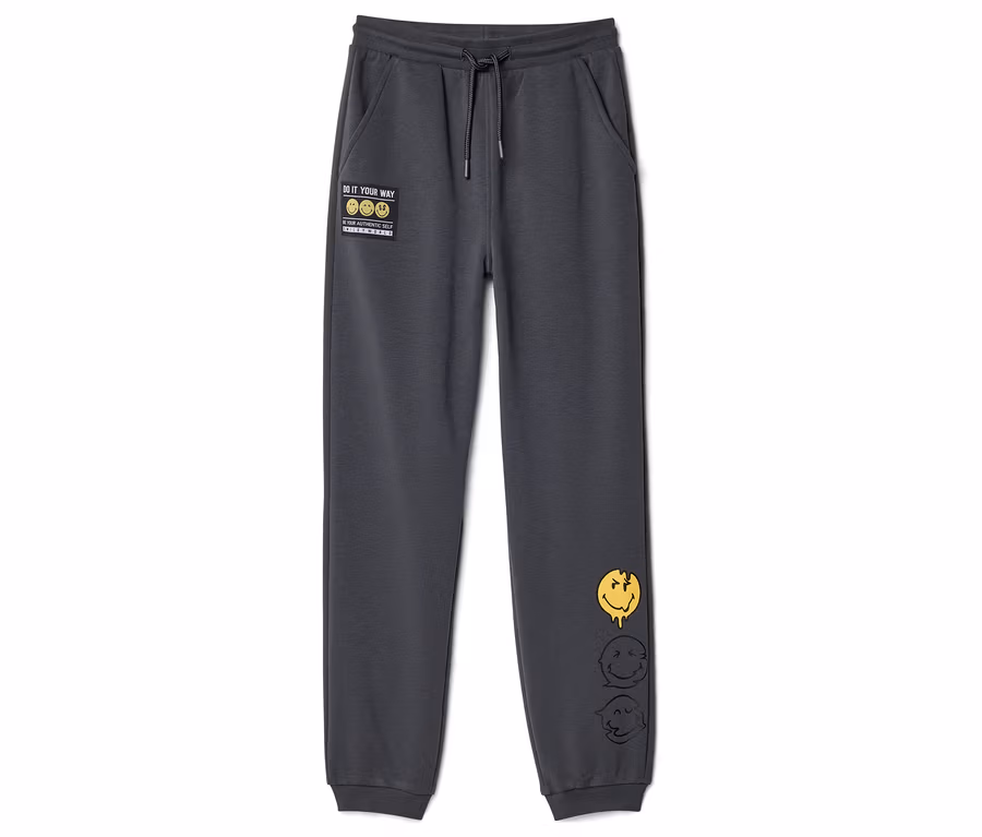 Dunkelgraue SMILEYWORLD® Kinder-Jogginghose mit Kordelzug, einem "DO IT YOUR WAY"-Patch und drei schmelzenden Smiley-Gesichtern am rechten Bein.