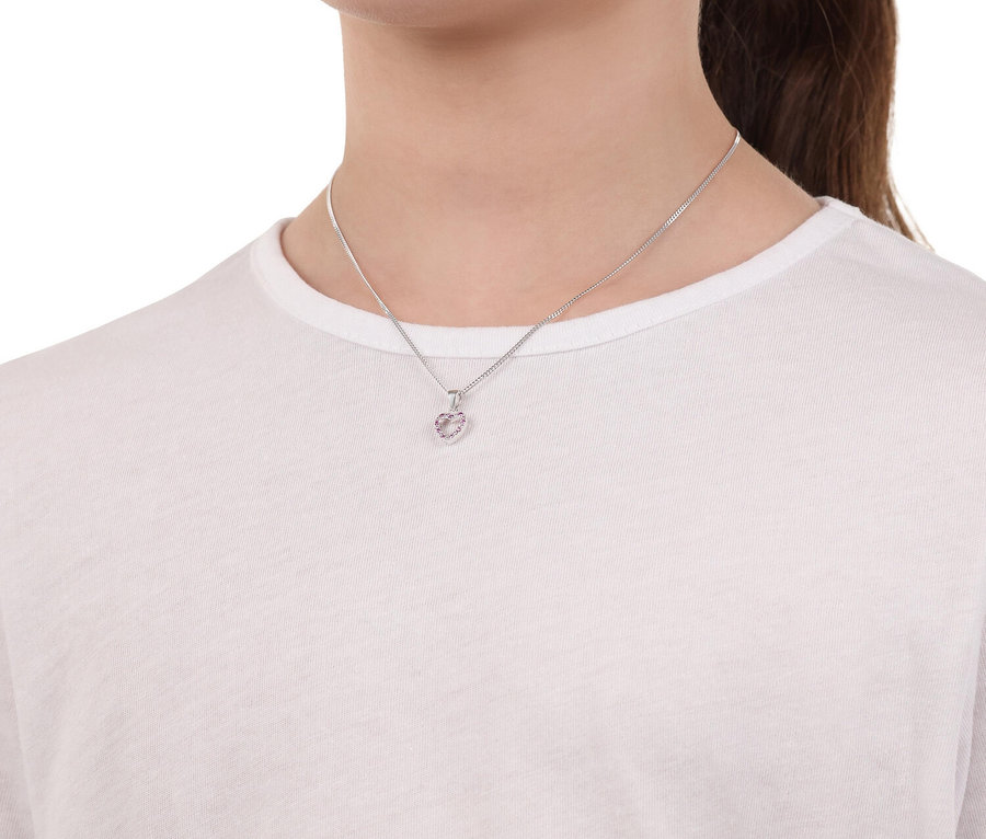 Junge Frau trägt eine silberne Halskette mit einem herzförmigen Anhänger, der mit rosa Steinen besetzt ist.