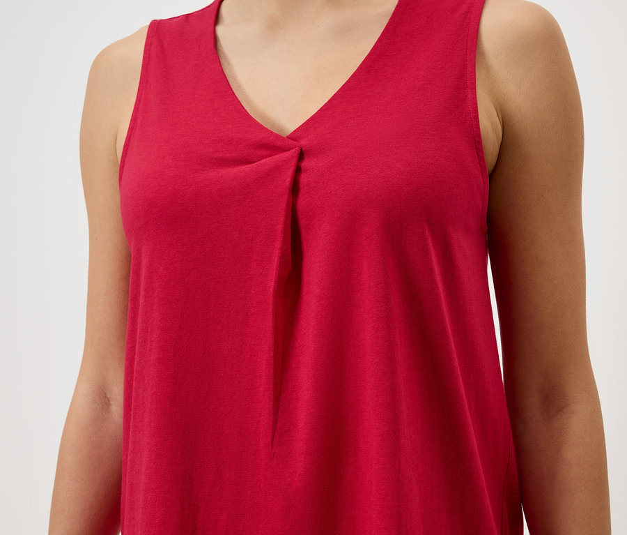 Nahaufnahme einer Frau, die ein ärmelloses, rotes V-Ausschnitt-Top trägt.