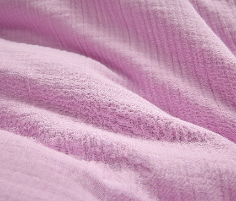Nahaufnahme eines zerknitterten, helllila Stoffes.