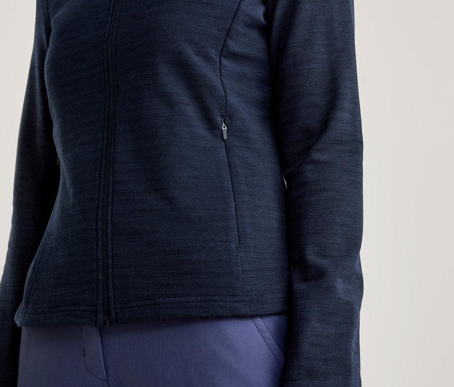 Nahaufnahme einer Frau, die eine marineblaue Jacke mit Reißverschluss und marineblaue Hose trägt.