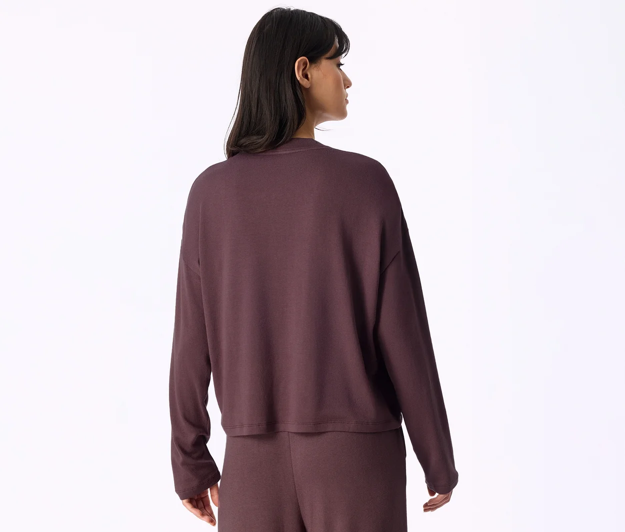 Frau von hinten, trägt ein dunkelviolettes Langarmshirt und eine passende Hose.