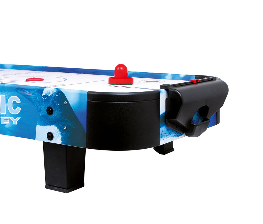 Nahaufnahme eines small foot Air-Hockey-Champion Tisches mit weißer Spielfläche, blauen Markierungen, rotem Puck und rotem Schläger. Die Tischseite zeigt ein blaues Pinguin-Design und eine schwarze Toröffnung.