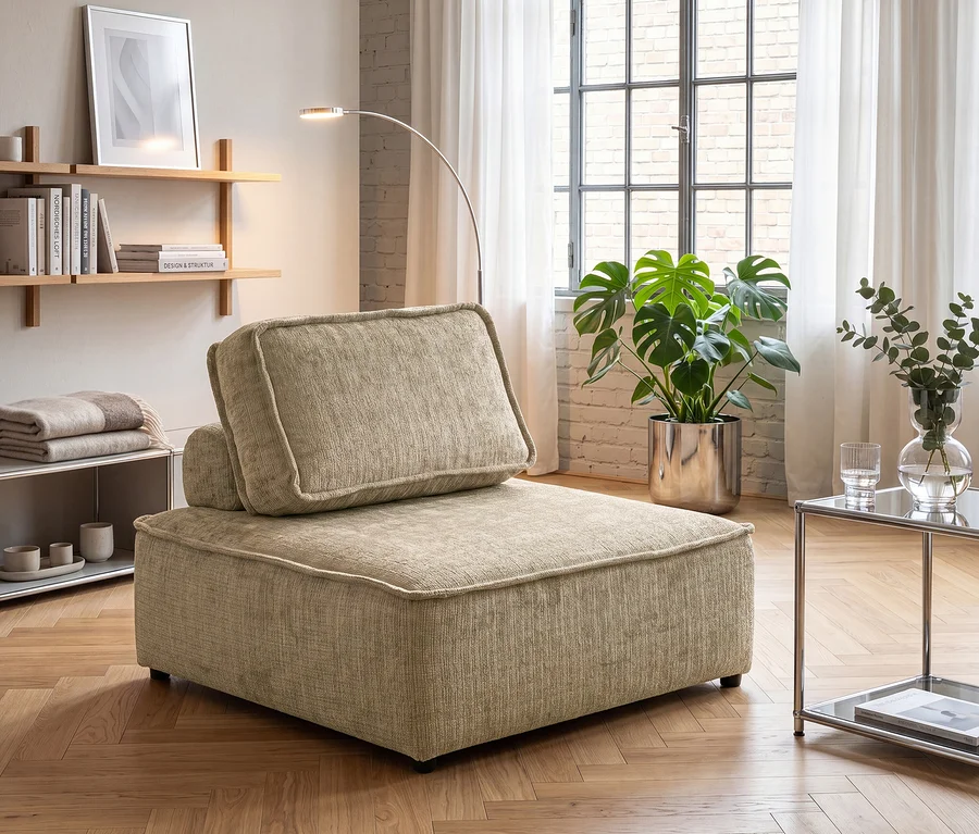 Beiger, modularer Sessel mit Kissen in einem Wohnzimmer mit Holzregalen, einer Monstera-Pflanze, einer Stehlampe und einem Glastisch.