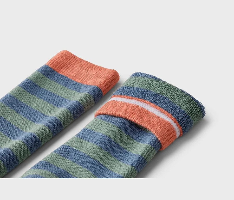 Nahaufnahme von zwei geringelten Socken in Grün und Blau mit orangefarbenem Bündchen.