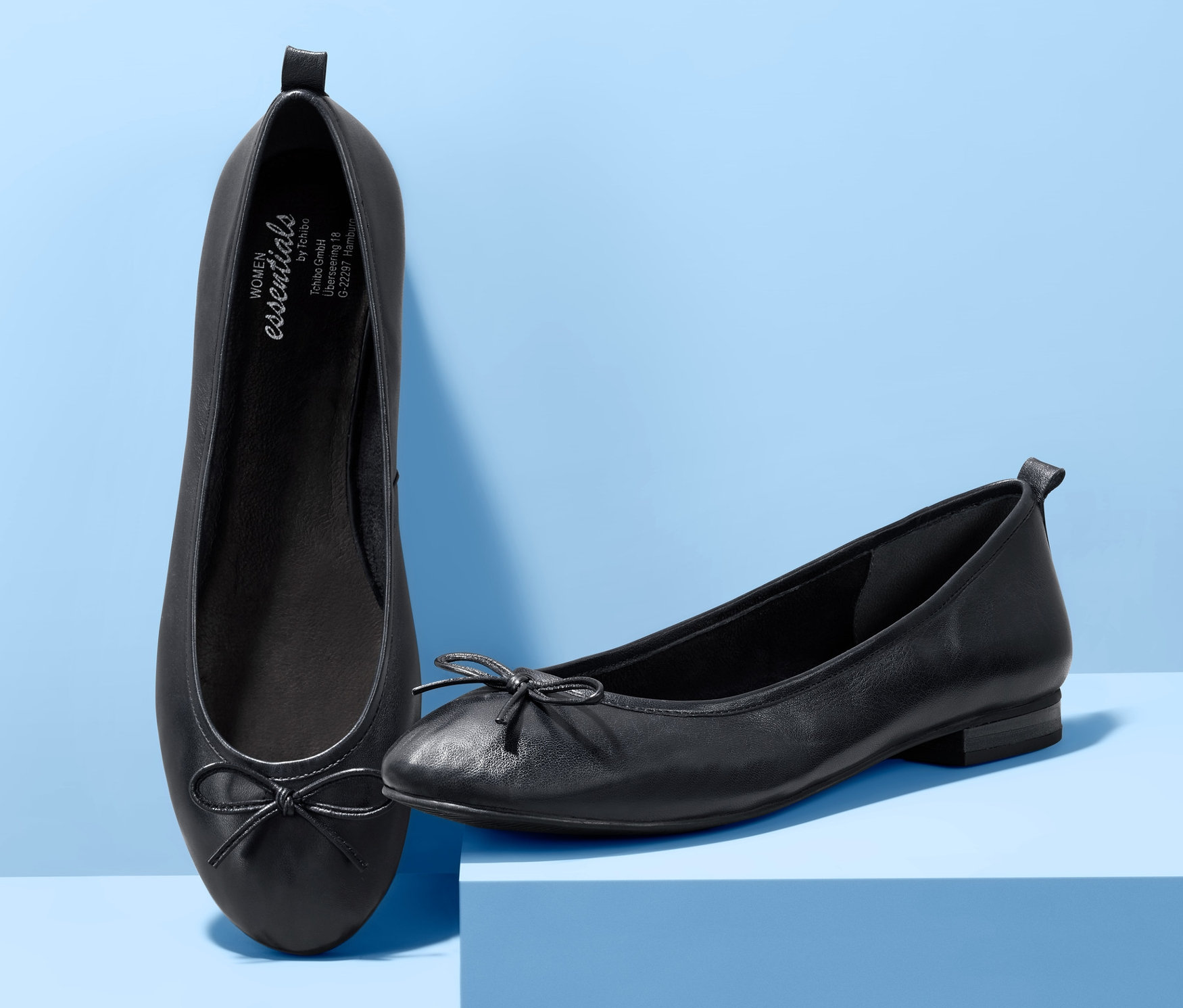 Zwei Leder-Ballerinas auf blauem Hintergrund.